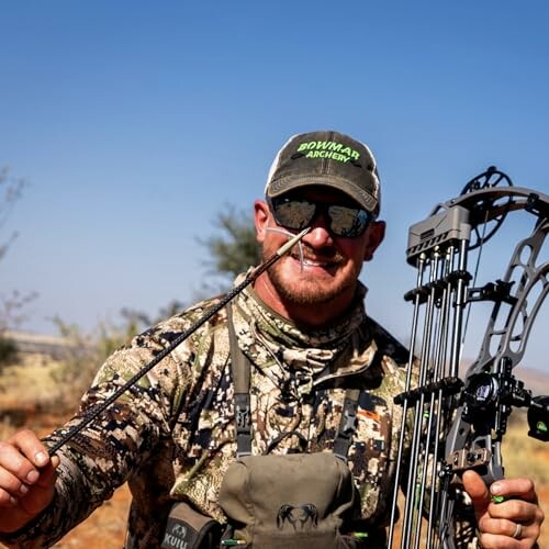 Hunter holding a compound bow and arrow outdoors.